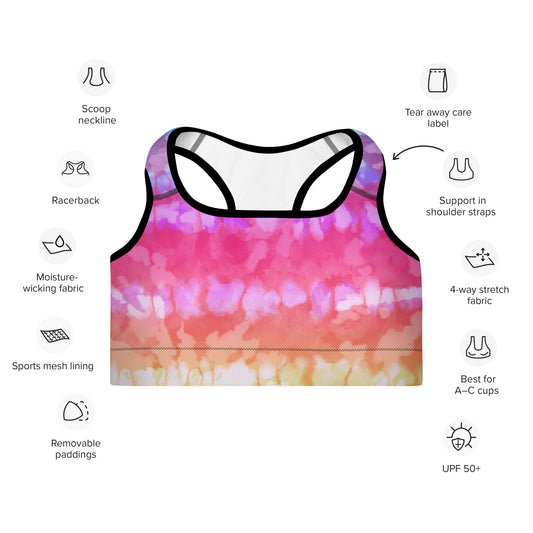 A sports bra with tie-dye stripes in a multicolor pattern, featuring a scoop neckline, racerback design, and shoulder straps with support material. It is marked with icons indicating the material used and the best fit for A-C cups.